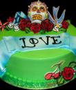 Tattoo Birthday Cake,  Green buttercream iced,  round decorated with tattoos. Roses, skull, birds, and a love banner. Everything on this cake is EDIBLE.  (Serves 8-80 party slices)